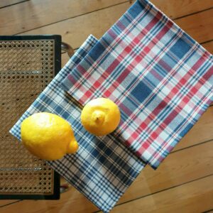 Deux citrons posés sur deux serviettes de table en tissu kelsch à carreaux rouge et bleu