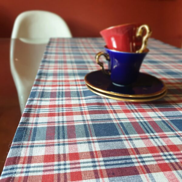 2 tasses empilées sur un chemin de table en tissu kelsch carreaux bleus et rouges